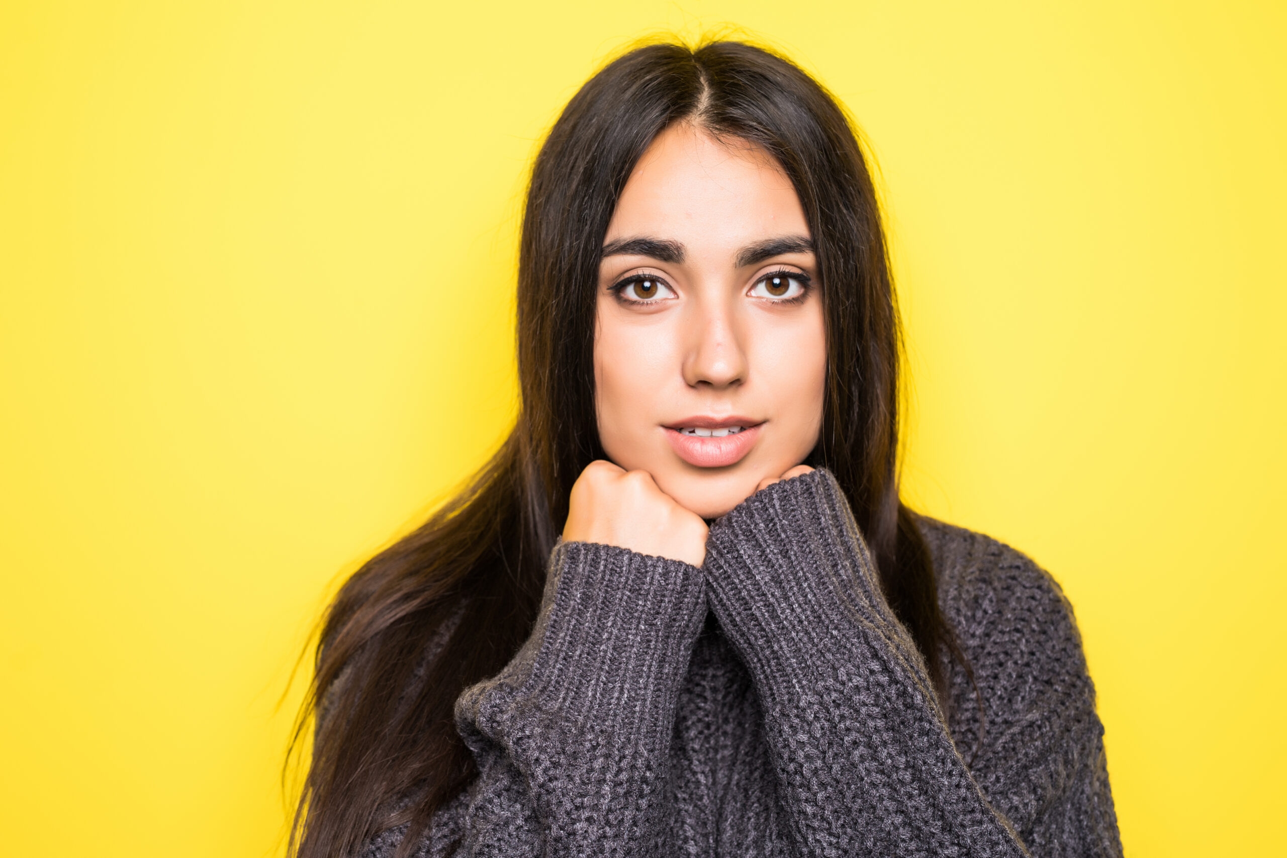 Beautiful young woman sweater smiling, and looking at camera on yellow background. Beautiful woman sweater smiling, and looking at camera on yellow background.